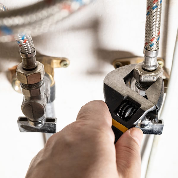 plumber hand fixes connection of tap by wrench