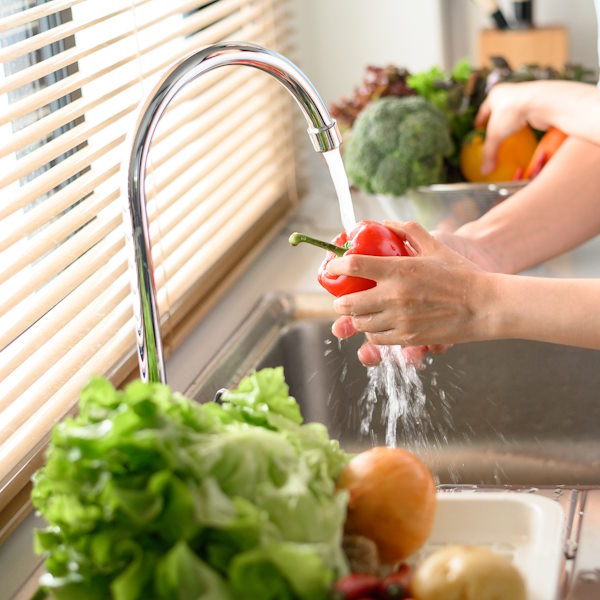 Couple washing vegetable in sink