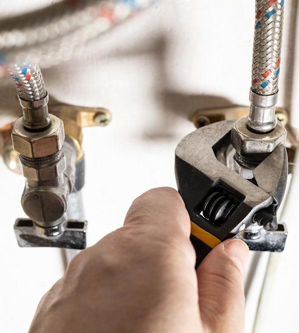 plumber hand fixes connection of tap by wrench